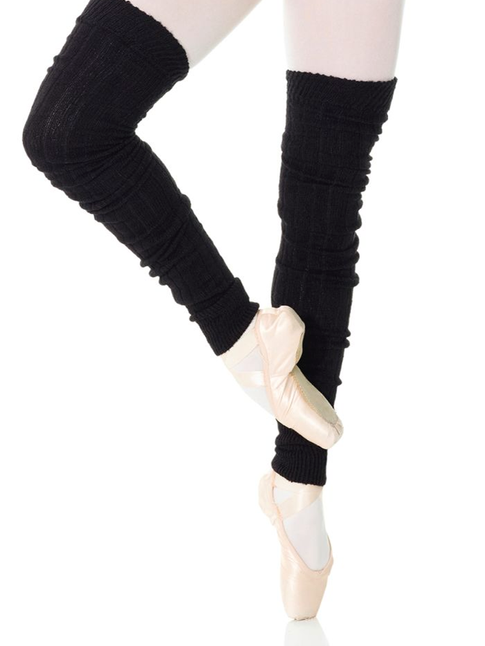 A close-up of a person's legs wearing ballet pink tights and upper thigh length, black legwarmers. They are balancing on one foot en pointe, the other leg lifted, turned out, and bent at the knee.