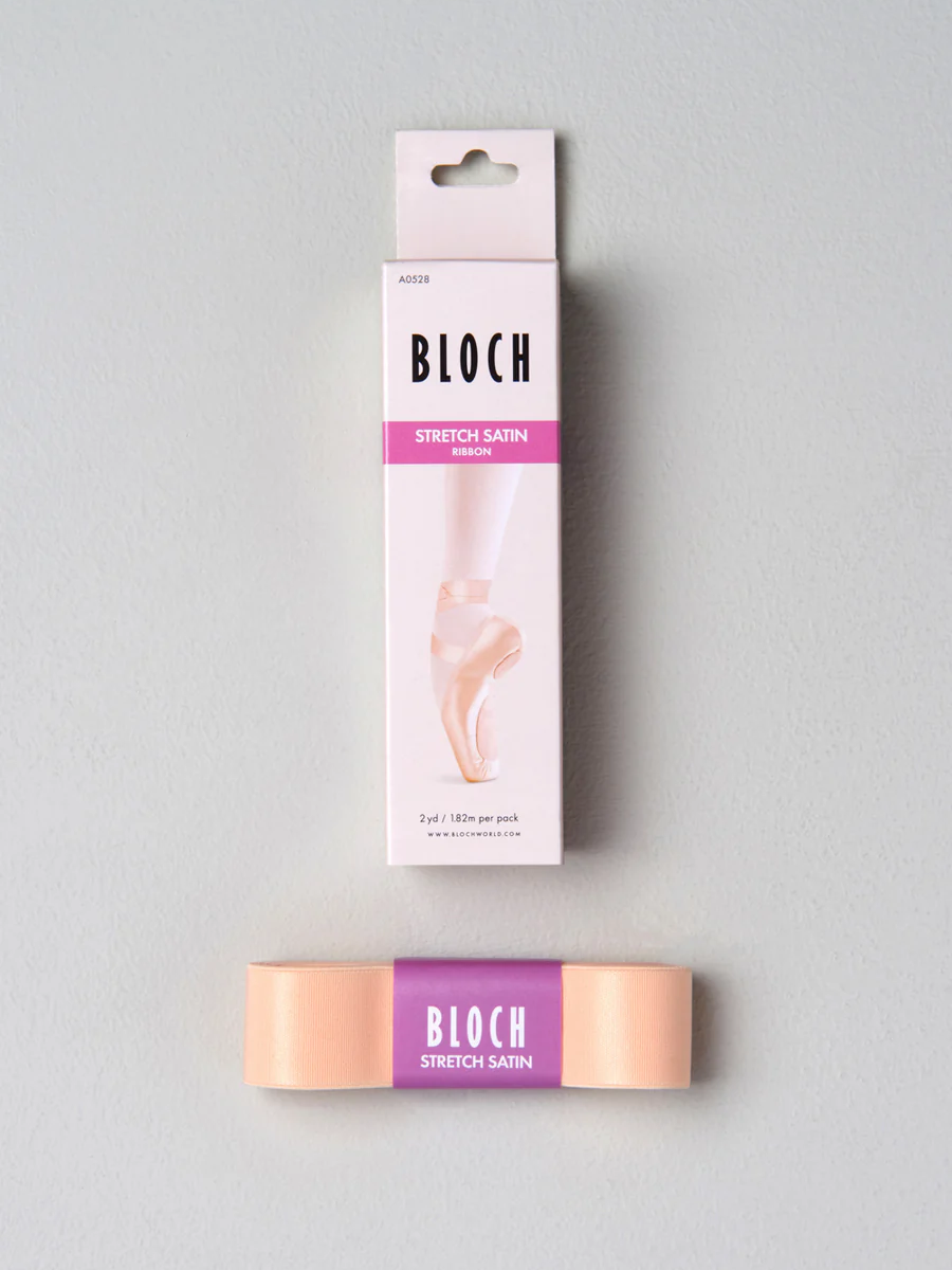 A light pink vertical package lays against a grey background. The pink stretch ribbon is placed below the box with Bloch branded wrapping.