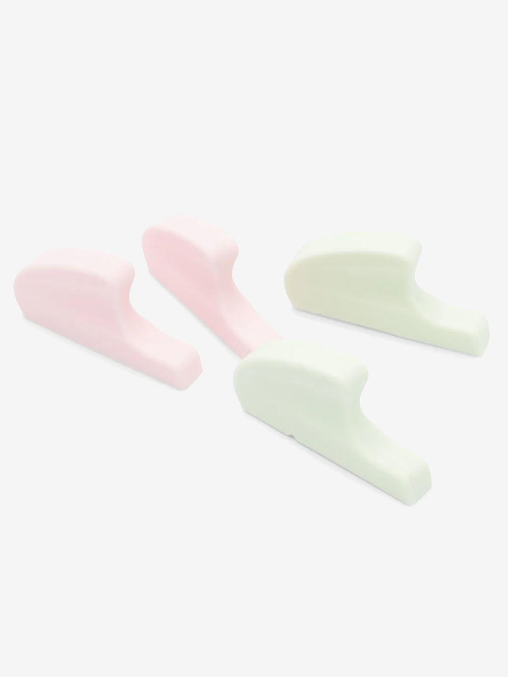 Four sleek spacers, two pink, two light green, sit upright against a plain light grey background.