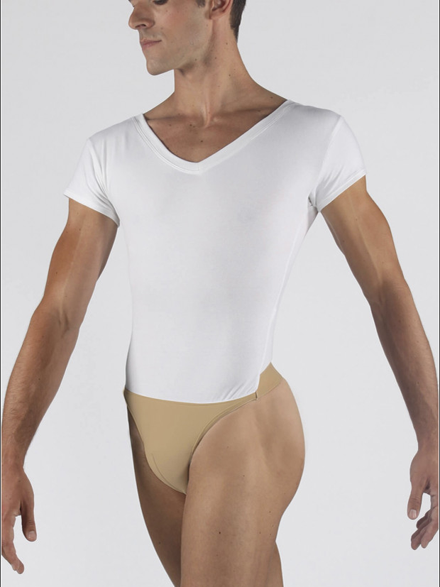 A man seen from his forehead to thighs. He stands angling his torso toward us, arms out to the side, wearing a v-neck white leotard with attached nude dance belt. The background is a plain light grey.