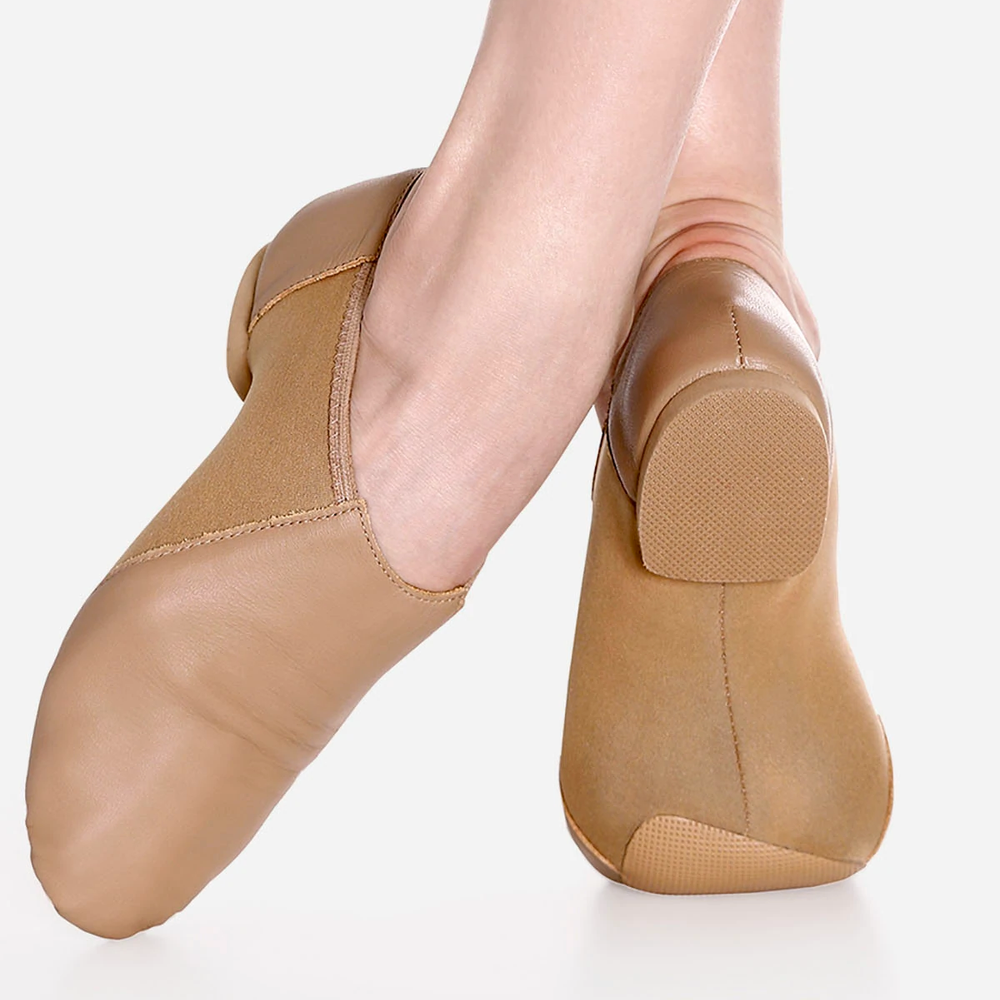 
                      
                        Close-up of a person's crossed legs wearing tan jazz shoes with a neoprene middle. One leg shows the front of the shoe, the other leg features the split-sole bottom.
                      
                    