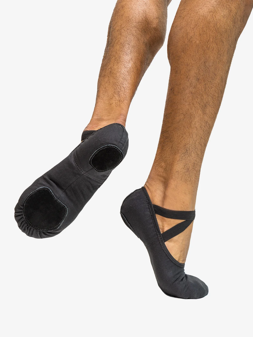 Close-up of a man's legs right foot on releve, back foot lifted showing the bottom of the black ballet shoe